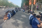 坐成一排,迟到的巴黎球迷用手机在香榭丽舍大道观赛